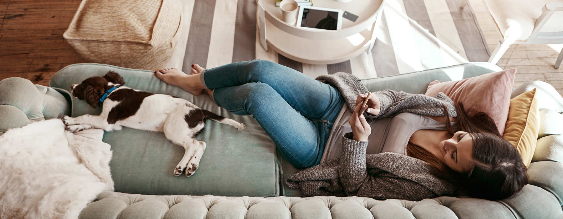 woman lays on her couch with her cute dog